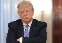 A serious-looking individual in business attire with crossed arms in a meeting setting
