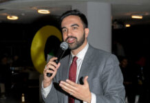 A man in a suit speaking into a microphone at an event